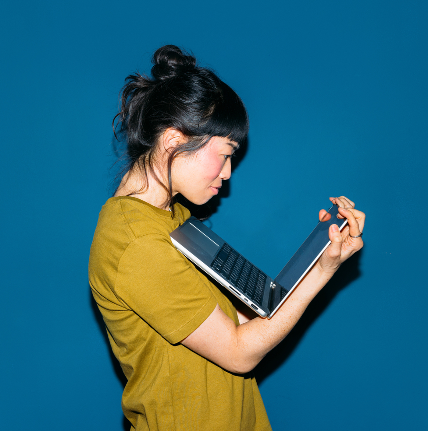 A woman staring down at a laptop she's holding